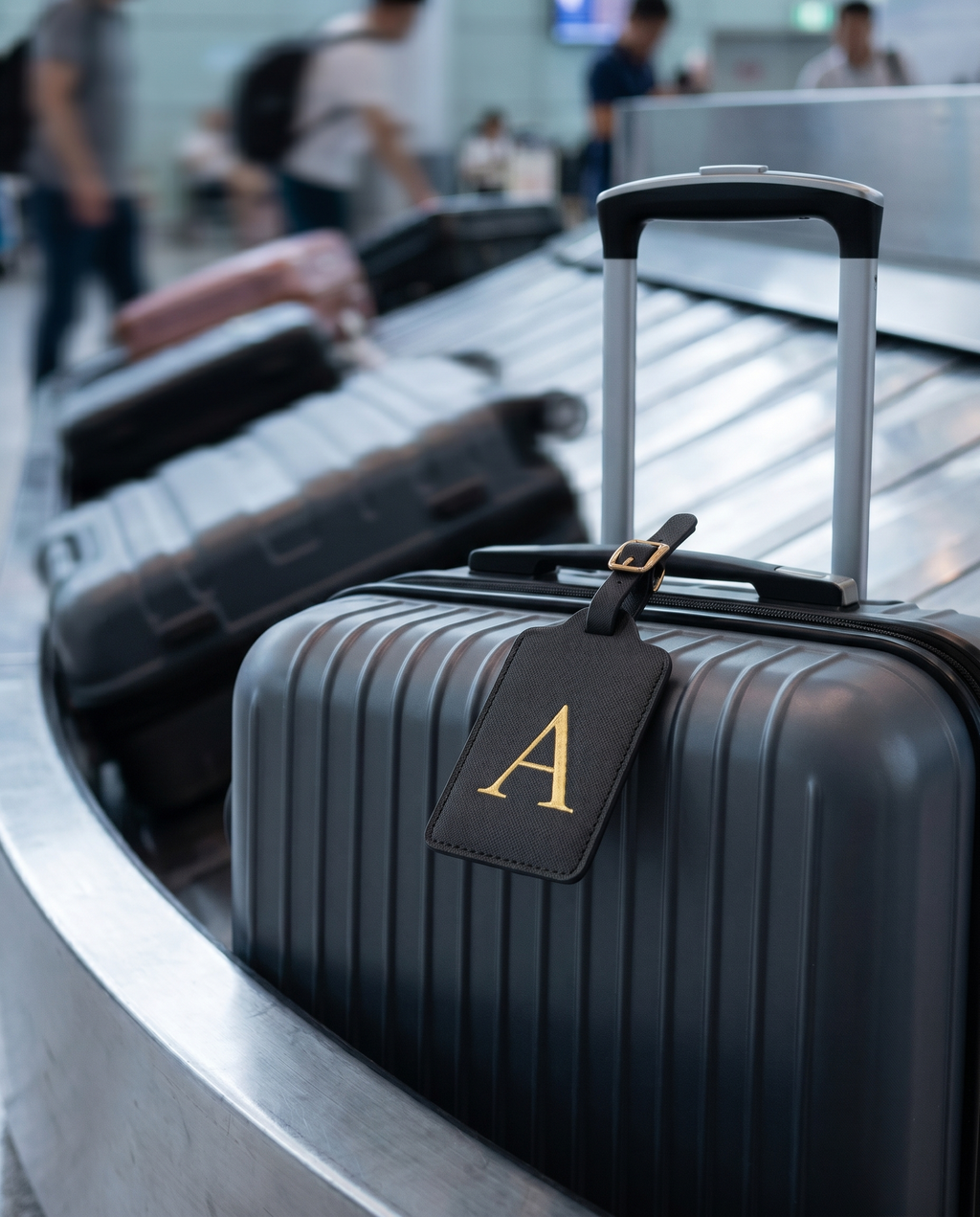 Étiquette bagage cuir Nomadly attachée à une valise à l'aéroport