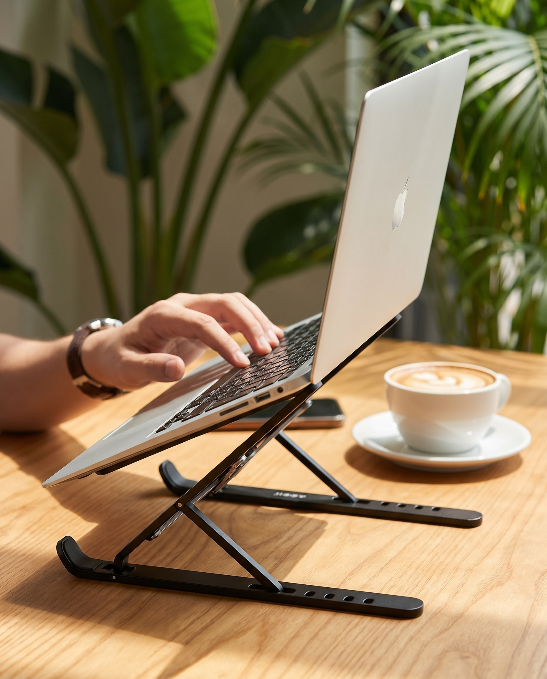 Support laptop pliable Nomadly installé sur une table de coworking ensoleillée